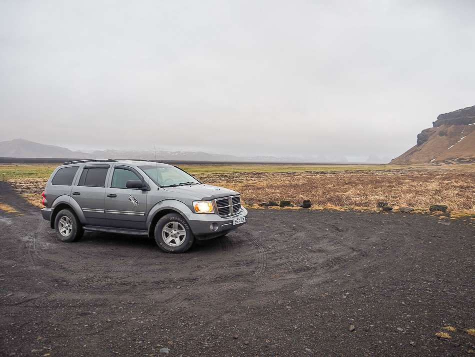 Kuku Campercan rental parked on gravel with brown landscape and an overcast day in the background.