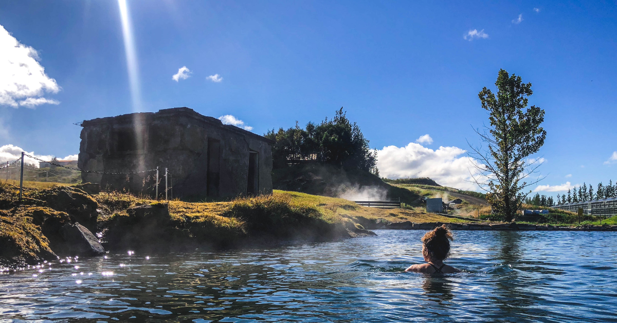 A woman swimming away from the camera at a thermal pool in Iceland called Secret Lagoon