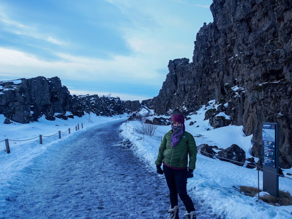 A woman standing on a snowy path with few crowds at Iceland's Thingvillir National Park in winter
