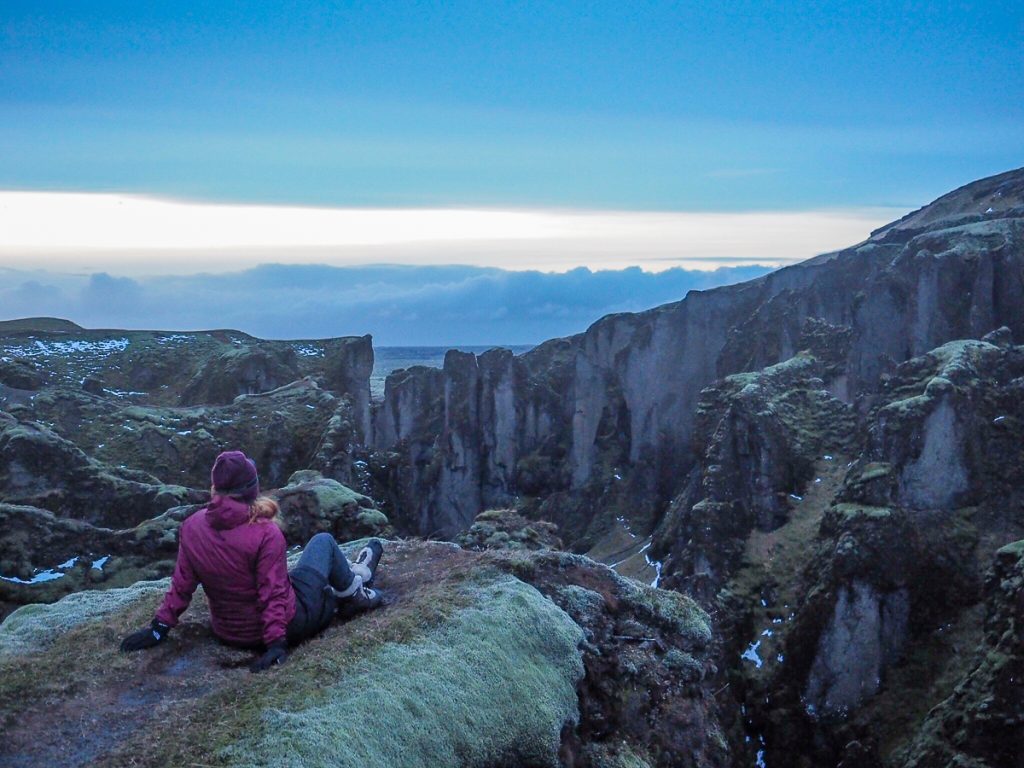 A woman sites atFjaðrárgljúfur Canyon in Iceland