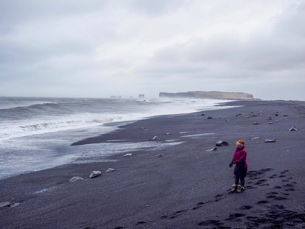 A woman stands at the Black Sand Beach in Iceland