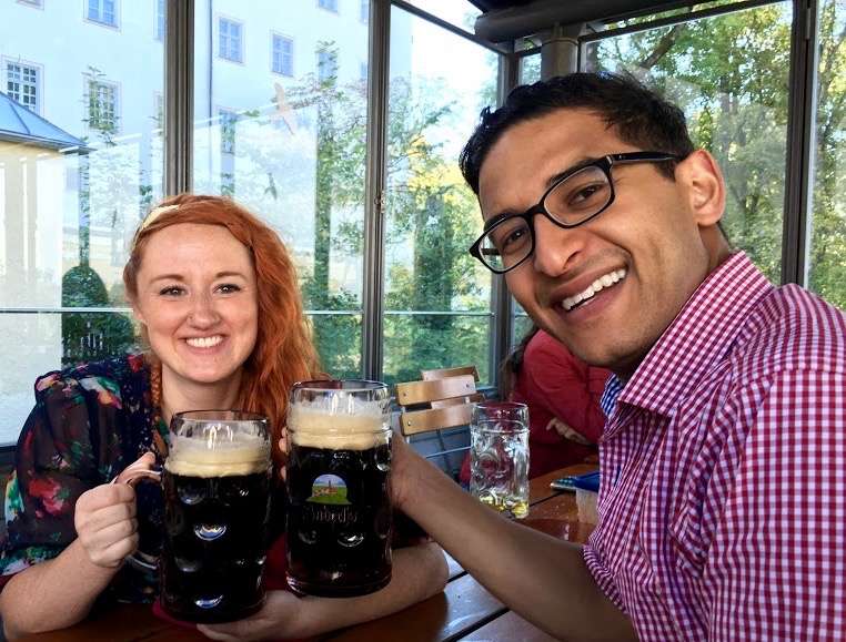 Sooz and Ganesh holding two big glasses of dark beer and smiling at the camera.
