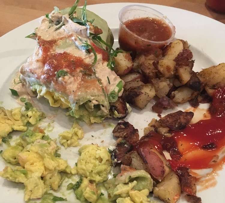 A close-up shot of a plate of half-eaten breakfast food including bacon, eggs and sauce.