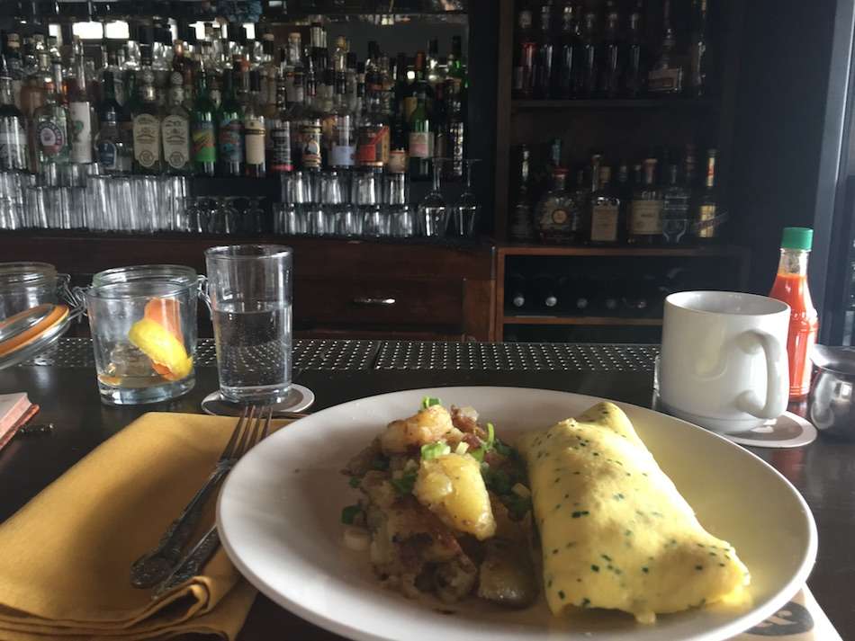 A plate with an omelette sitting on a bar with drinks stacked in the background.