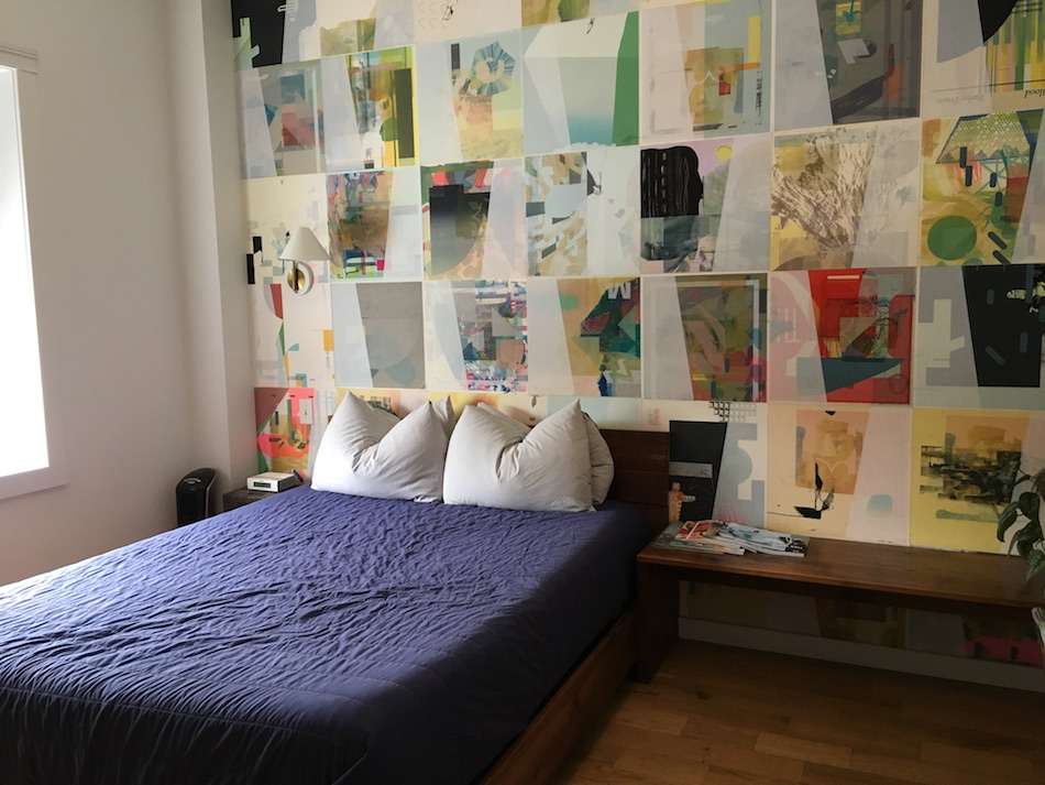 A double bed in a room with a wall covered in posters.