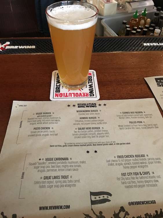 A glass of beer sitting on a coast above a paper menu at Revolution Brewing in Chicago.