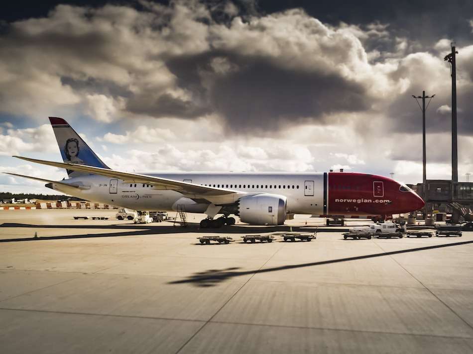 A Boeing Dreamliner air craft on the tarmac at an airport on a cloudy day.