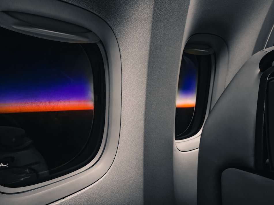 Airplane windows at sunset with a tiny bit of color on the horizon.