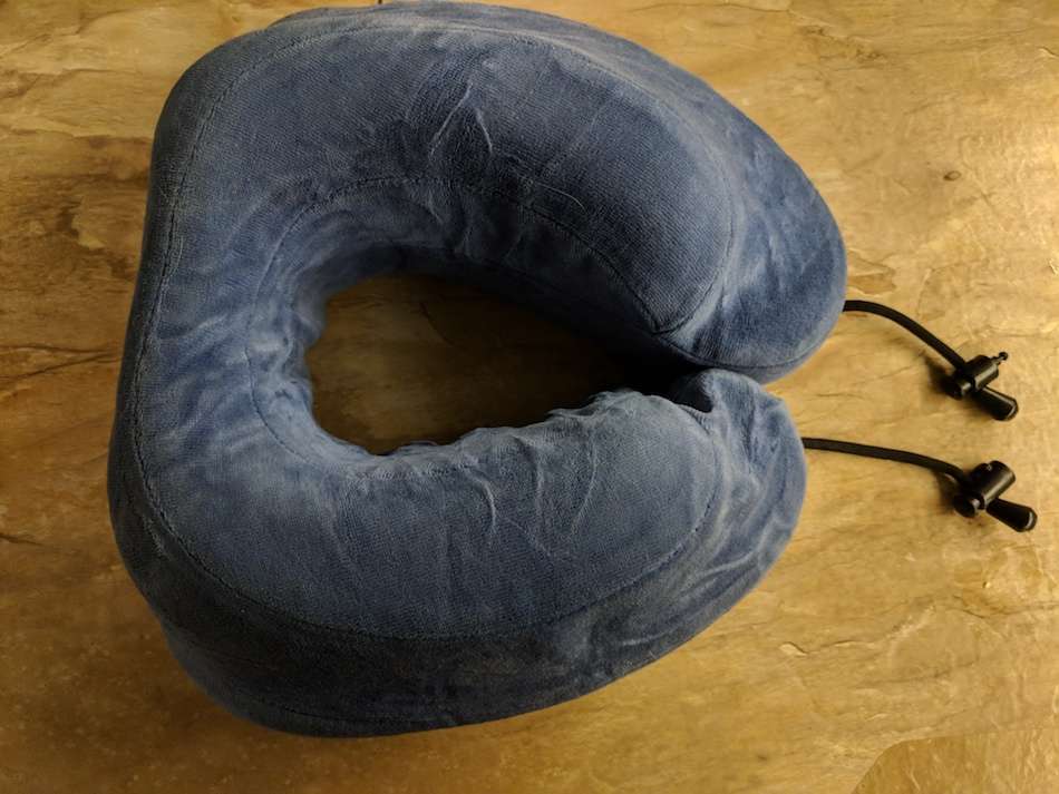 A dark blue travel neck pillow on a wooden surface.