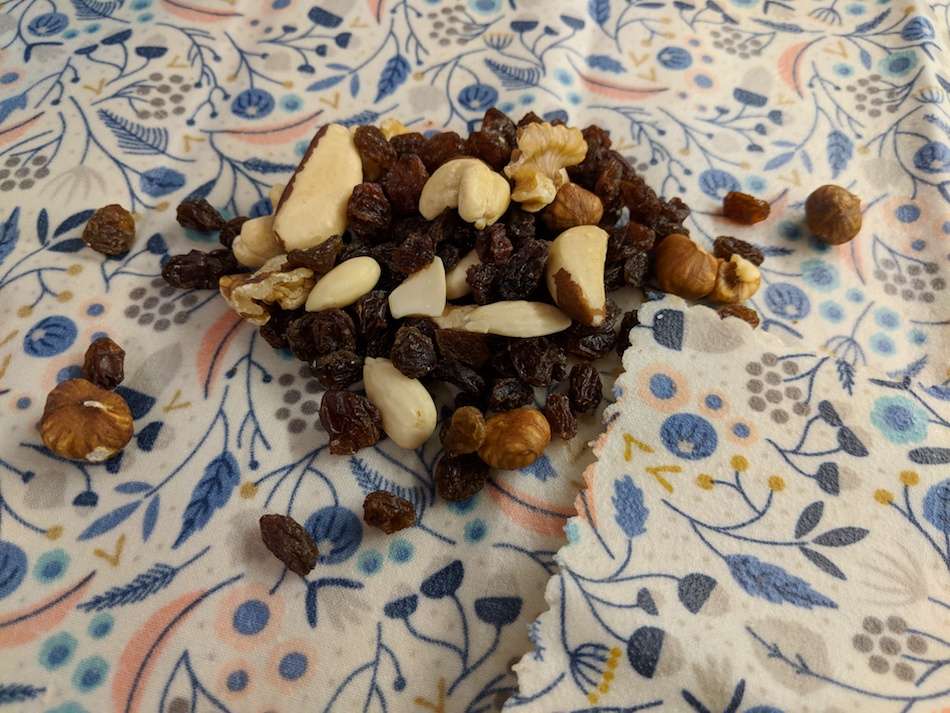 A handful of nuts and sultanas sitting on a patterned beeswax wrap.