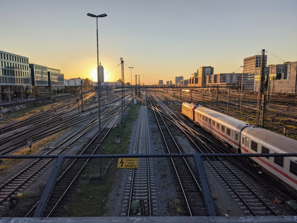 An overhead shot of lots of train tracks and one train taken from a  bridge at sunset.