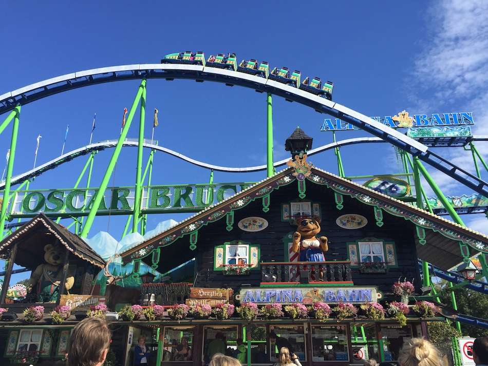 A rollercoaster above a wooden building selling prizes at a German volksfest.
