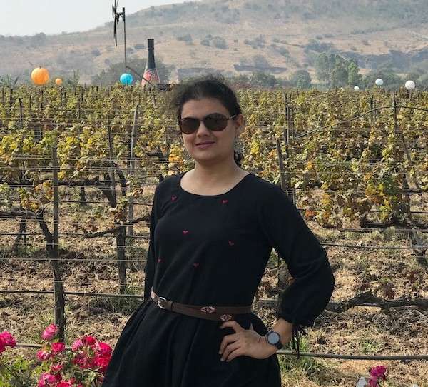 Ketki stands in front of vineyards
