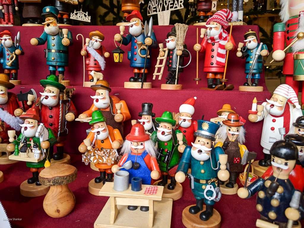 A close up of wooden Christmas figurines on shelves of red material.