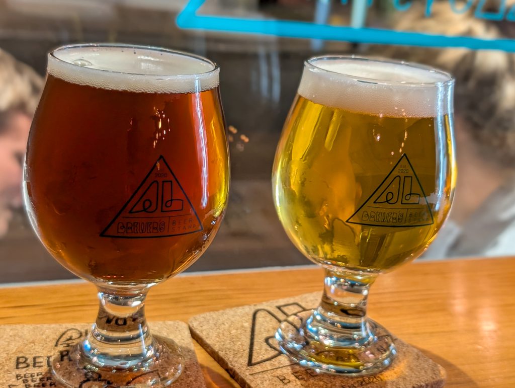 A close-up shot of two glasses of different colored beer on a bar.