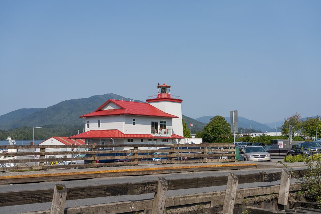 A white building with red roofs with blue skies and mountains behind.