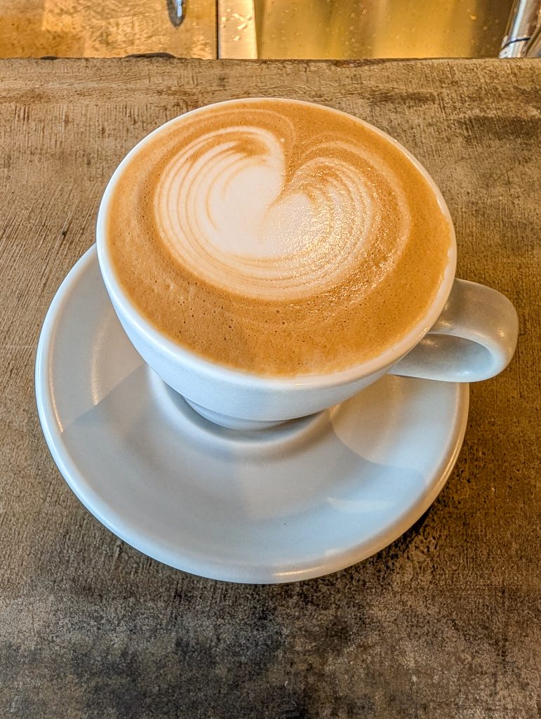 A close-up shot of coffee in a white mug on a saucer.