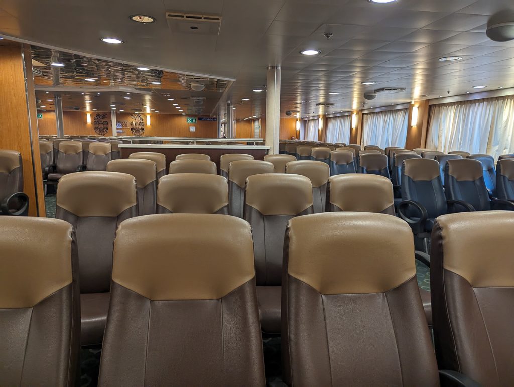 Rows of empty brown leather seats in a room with wooden walls and closed curtains.