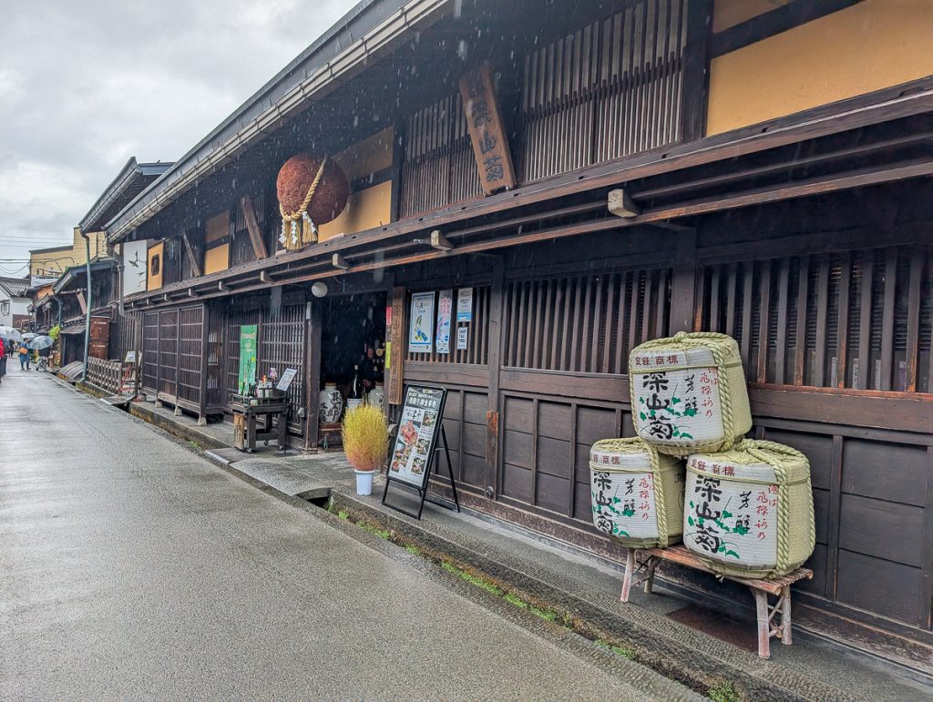 The Funasaka Brewery entrance with giant cedar ball and a sign showing meat served in the restaurant.