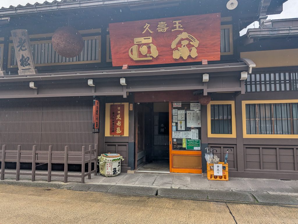The simple entrance to Hirase Brewery, with a huge wooden sign, cedar ball and a basket for umbrellas.