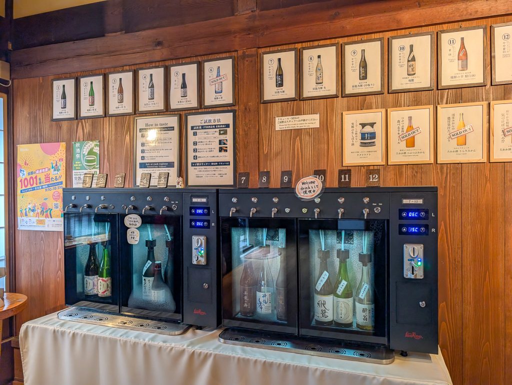The sake 'vending' machine wall at Hirata Brewery, with pictures on the wall of the different sakes to try.