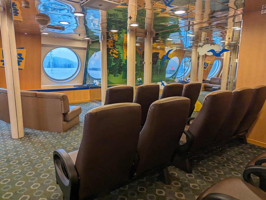 Comfy chairs facing a porthole window in the kid's area on board a BC Ferry.