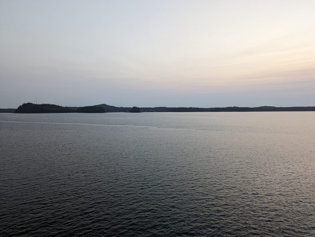 A view of water with land in the distance at dusk.