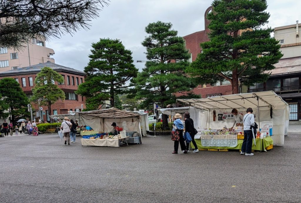 Some covered stalls and locals at the morning market in Takayama on a rainy day.