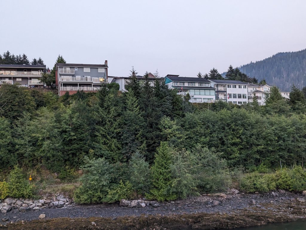 A view of big houses on a wooded hill as seen from offshore.