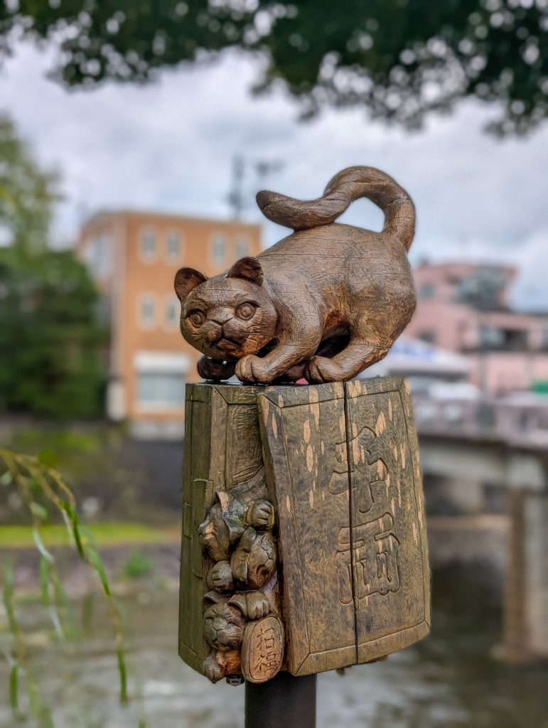 A close-up shot of a yew carving next to a river of a cat on a book.