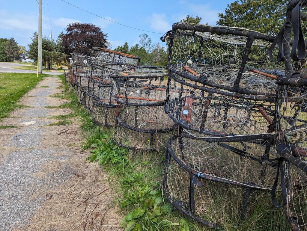 A bunch of empty crabbing pots stacked up next to the footpath of a street.