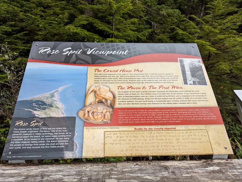 An informational sign on a trail with text and images about the Rose Spit Viewpoint and stories of the Haida people.