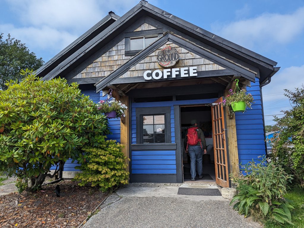 A wooden building with blue walls and a sign saying "The Ground Coffee."