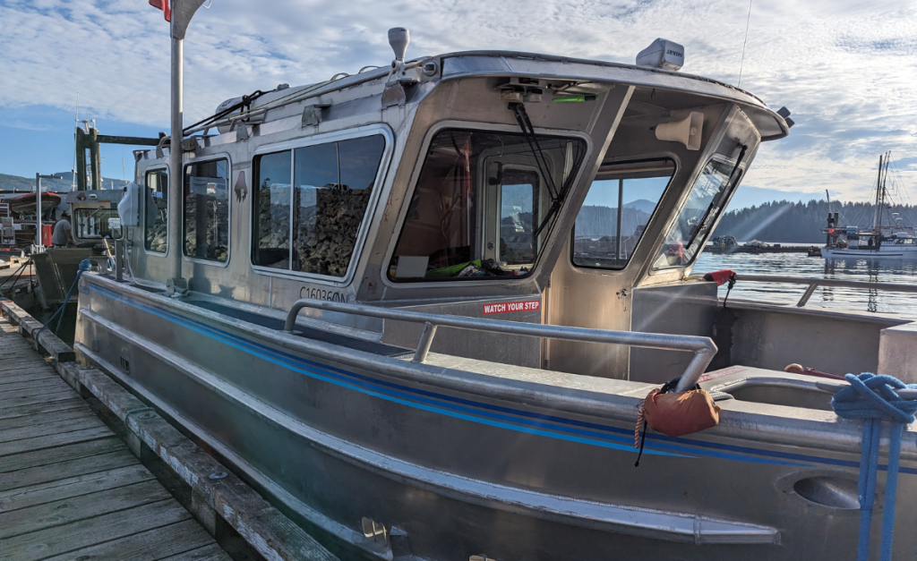 A close-up of a metal looking boat with water and more boats in the background.