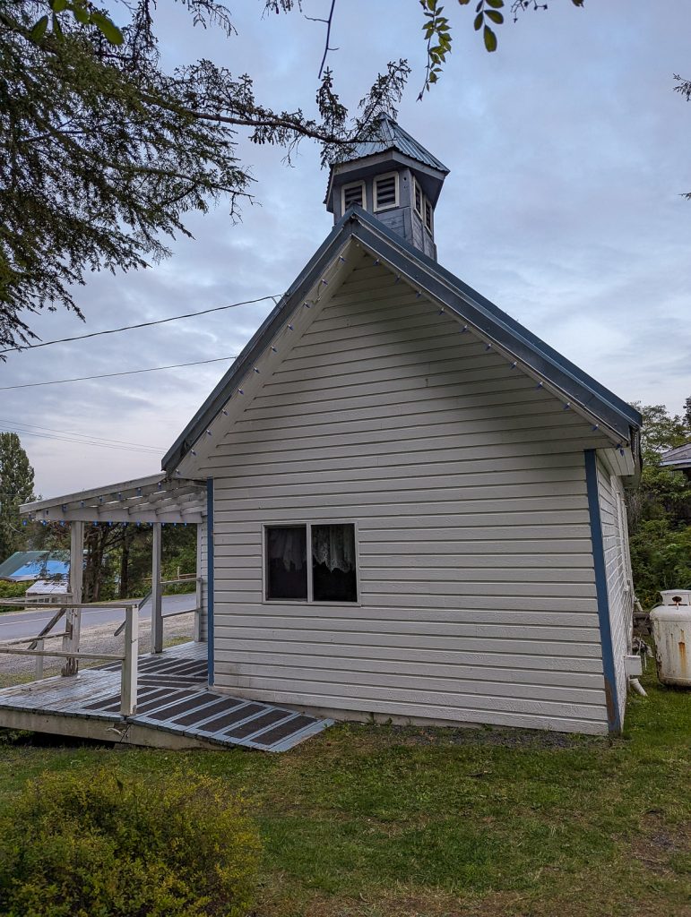 A white wooden building with a cute little tower on top.