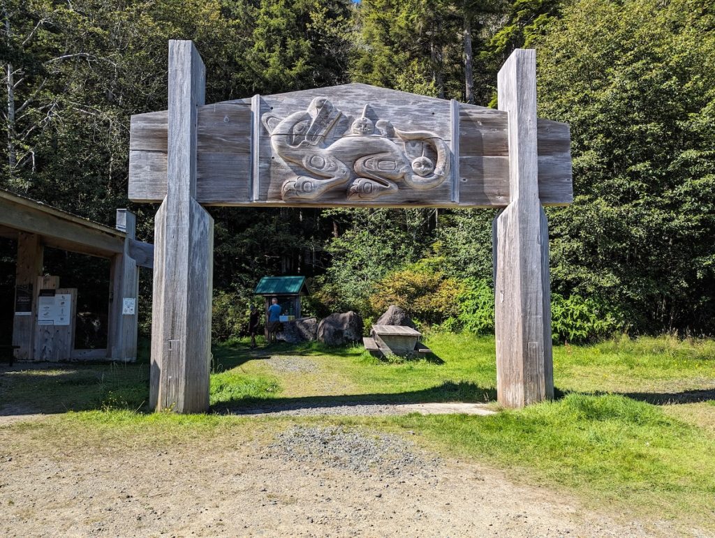 A wooden carving of an animal held up by two wooden struts with forest behind.