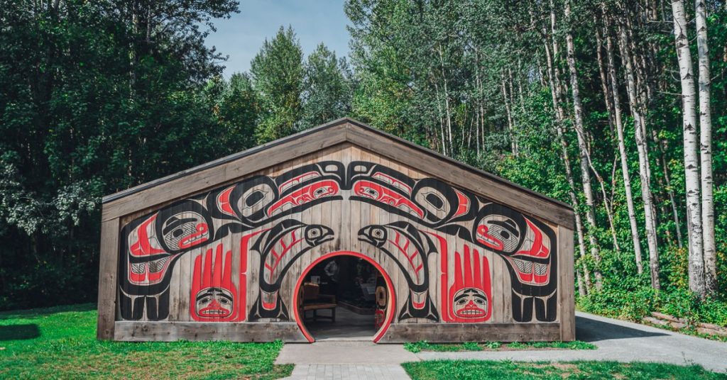 A wooden building decorated with stylised black and red tribal symbols of fish and animals.