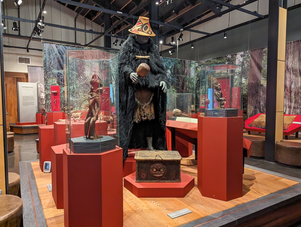A museum exhibit showing a Nisga'a shaman's outfit featuring a bear cloak and other ceremonial items.