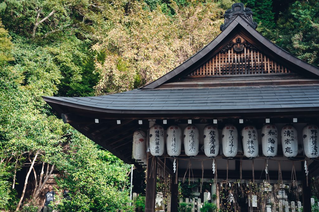 A more rural shrine in kyoto with paper lanterns hanging from the roof.