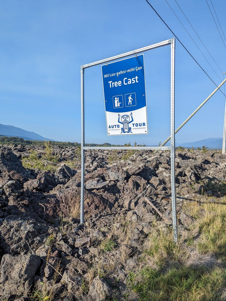 An Auto Tour sign for a Tree Cast standing among rocks on the Nisga'a Auto Tour.