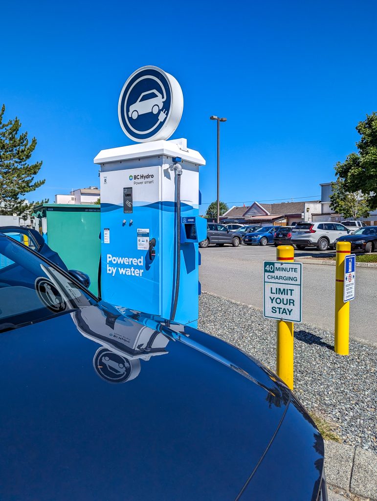 The bonnet of a dark blue car parked next to a BC Hydro electric vehicle charging station.