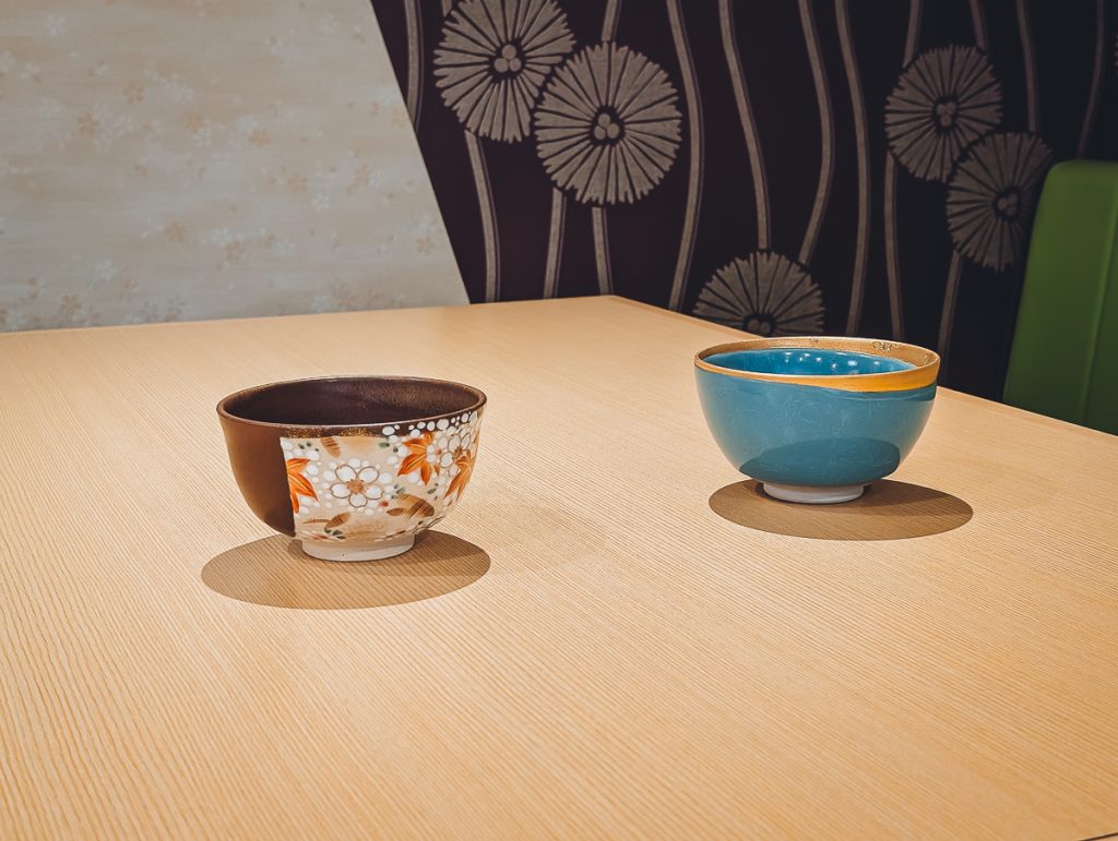 Two pretty ceremonial matcha bowls sitting on a wooden surface.