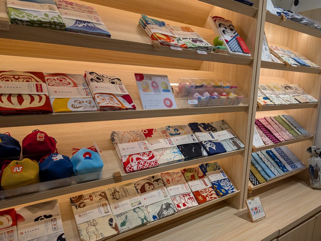 Plastic-free fabric, clothing and souvenirs on wooden shelves in Japan.