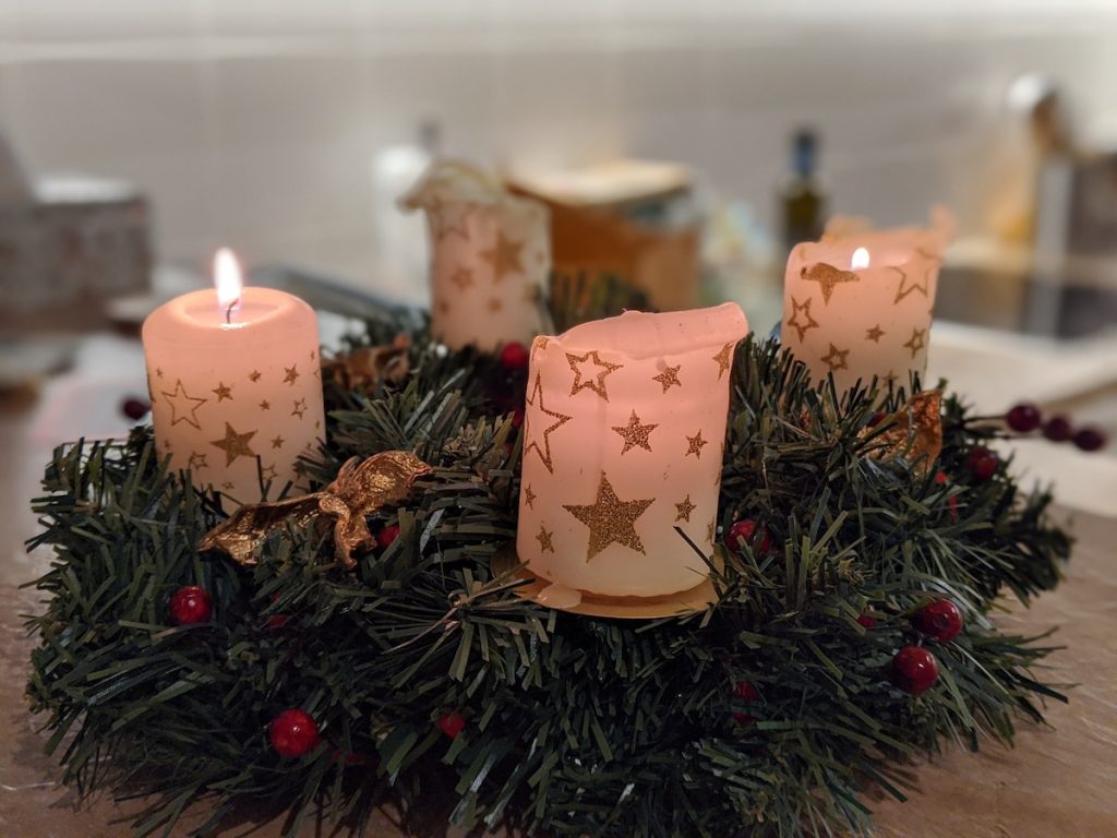 An advent wreath with two out four white candles with gold stars lit.