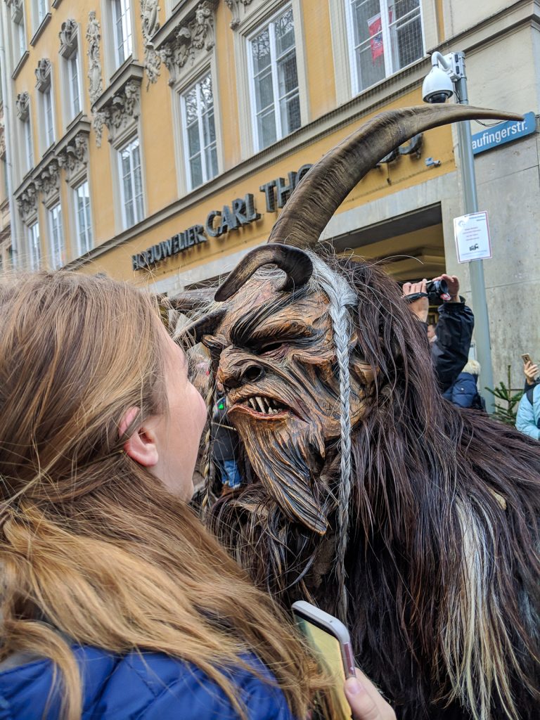 A costumed horned figure with a mask terrifies a woman during the Krampus Run in Munich
