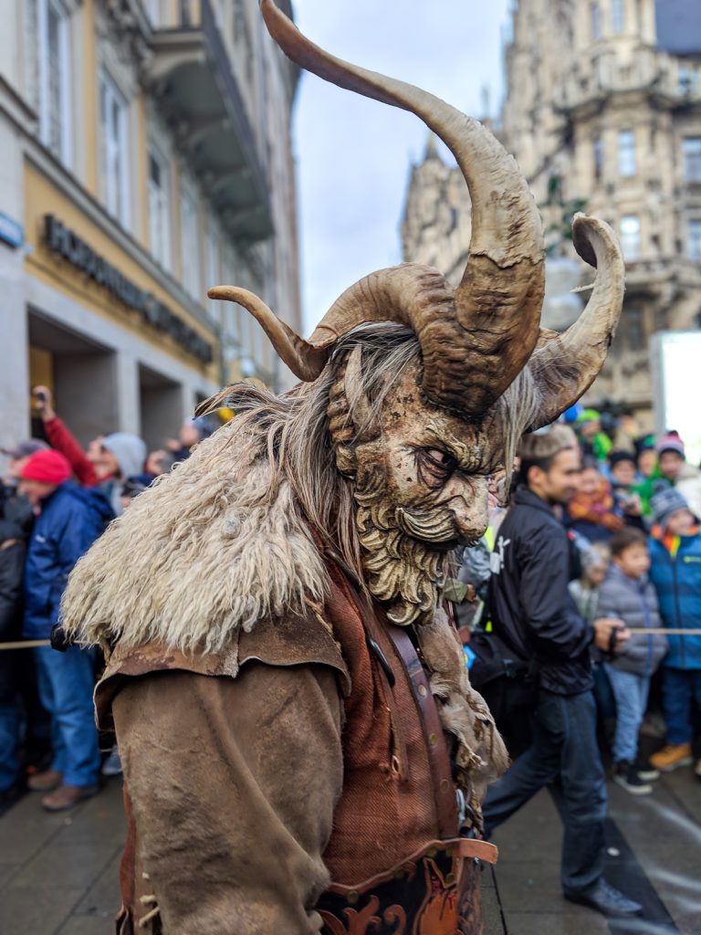 a costumed person with goat-like horns depicting krampus in Munich's Krampuslauf