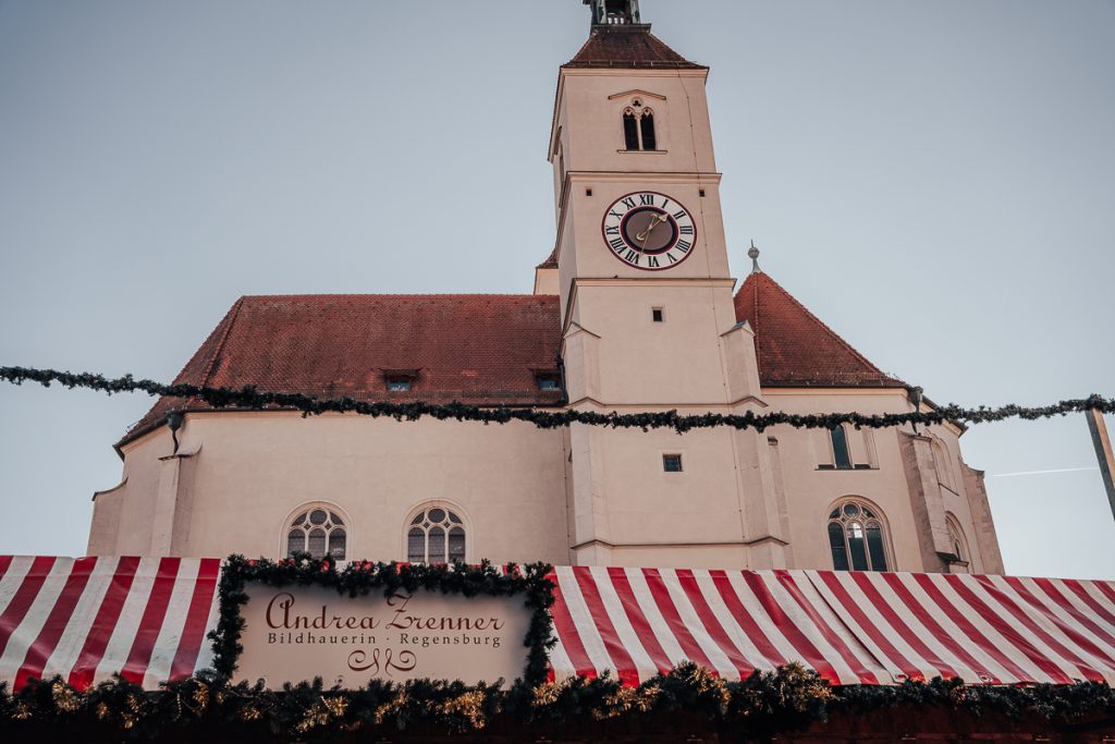 The top of a Christmas market stall in Regensburg in front of the church tower in Neupfarrplatz.