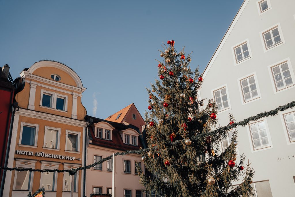 A decorated Christmas tree in front of buildings including a hotel in Neupfarrplatz, Regensburg.