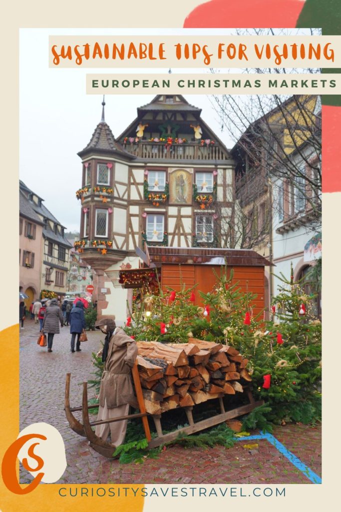 A photo of a Christmas display featuring wood on a sled in front of decorated pine trees and decorated timber buildings, with text at the top that reads "Sustainable travel tips for visiting European Christmas Markets."