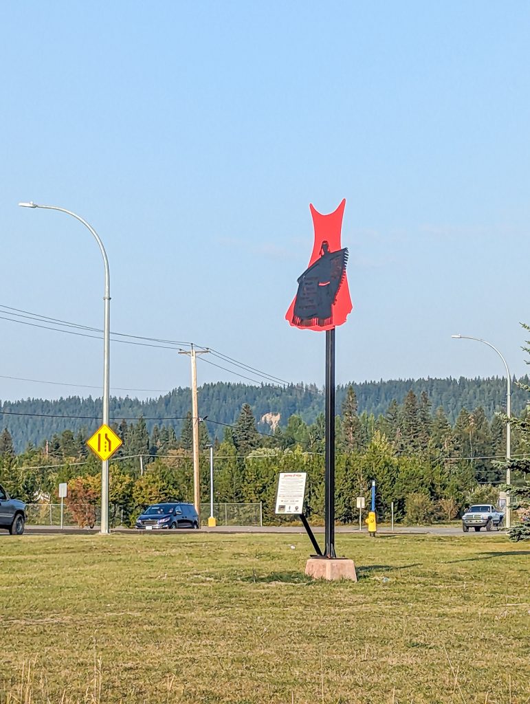 A red dress sign on a post next to a road.
